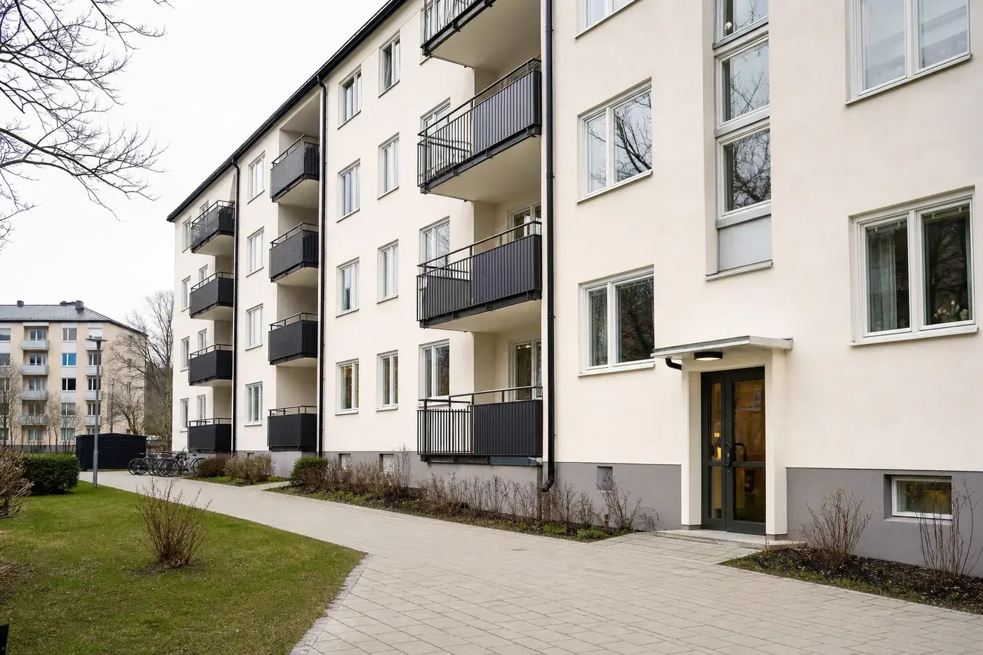 Modern fastighet med gul putsfasad och rena fasaddetaljer.